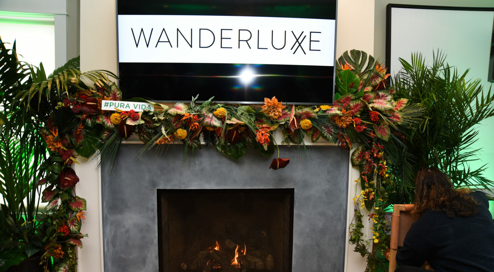 A decorative floral arrangement over a fireplace with the hashtag '#PURA VIDA' at an event venue.