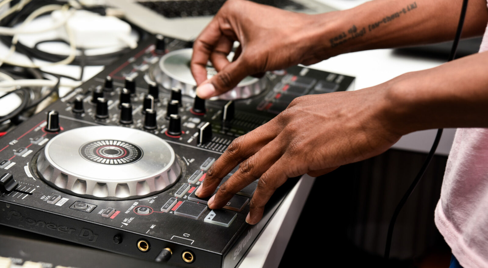 A DJ adjusting settings on a music mixing console at a lively event.