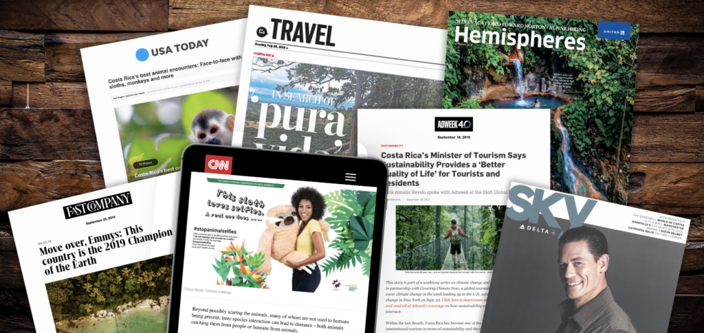 The image showcases a collection of magazine covers and articles spread out on a wooden surface, prominently featuring coverage of Costa Rica in notable publications such as USA Today, Travel, and Hemispheres, highlighting the country's rich biodiversity and commitment to sustainability.