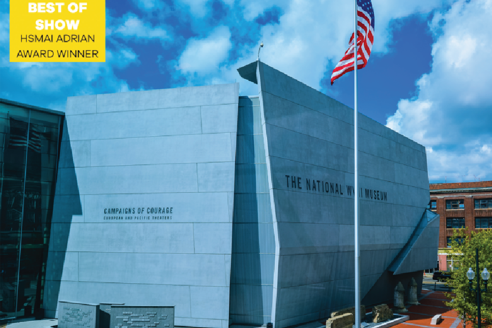 Exterior view of The National WWII Museum in New Orleans, showcasing the modern architecture of the 'Campaigns of Courage' pavilion under a clear blue sky, with the American flag proudly displayed.